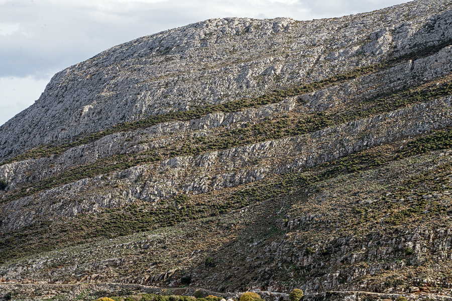 Interlayered schist and marble, with the vegetation more prominent on the schist.